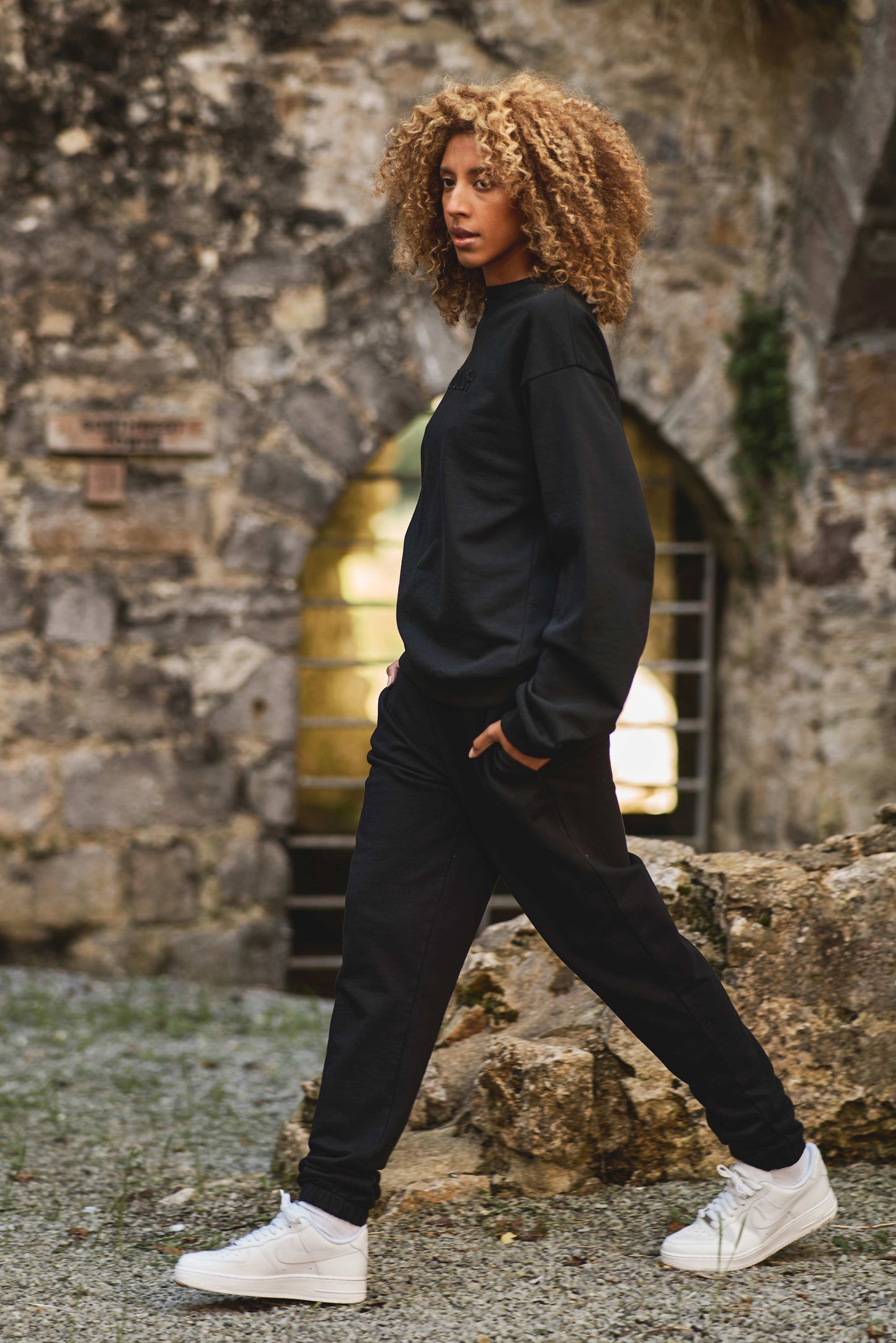 model walking in matching black luxury sweatshirt and joggers with white trainers