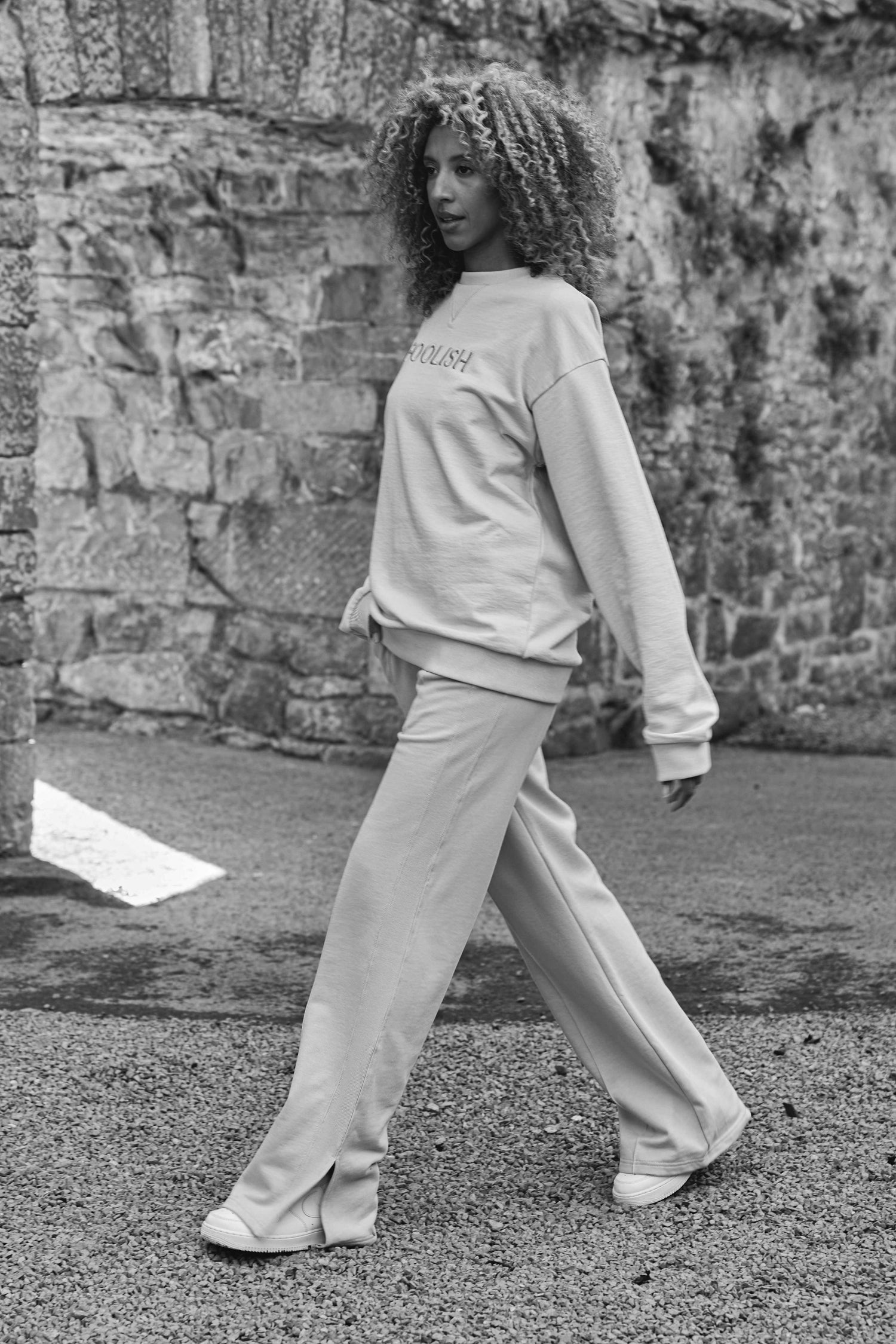 black and white image of model walking in luxury sweatshirt and joggers set in cream