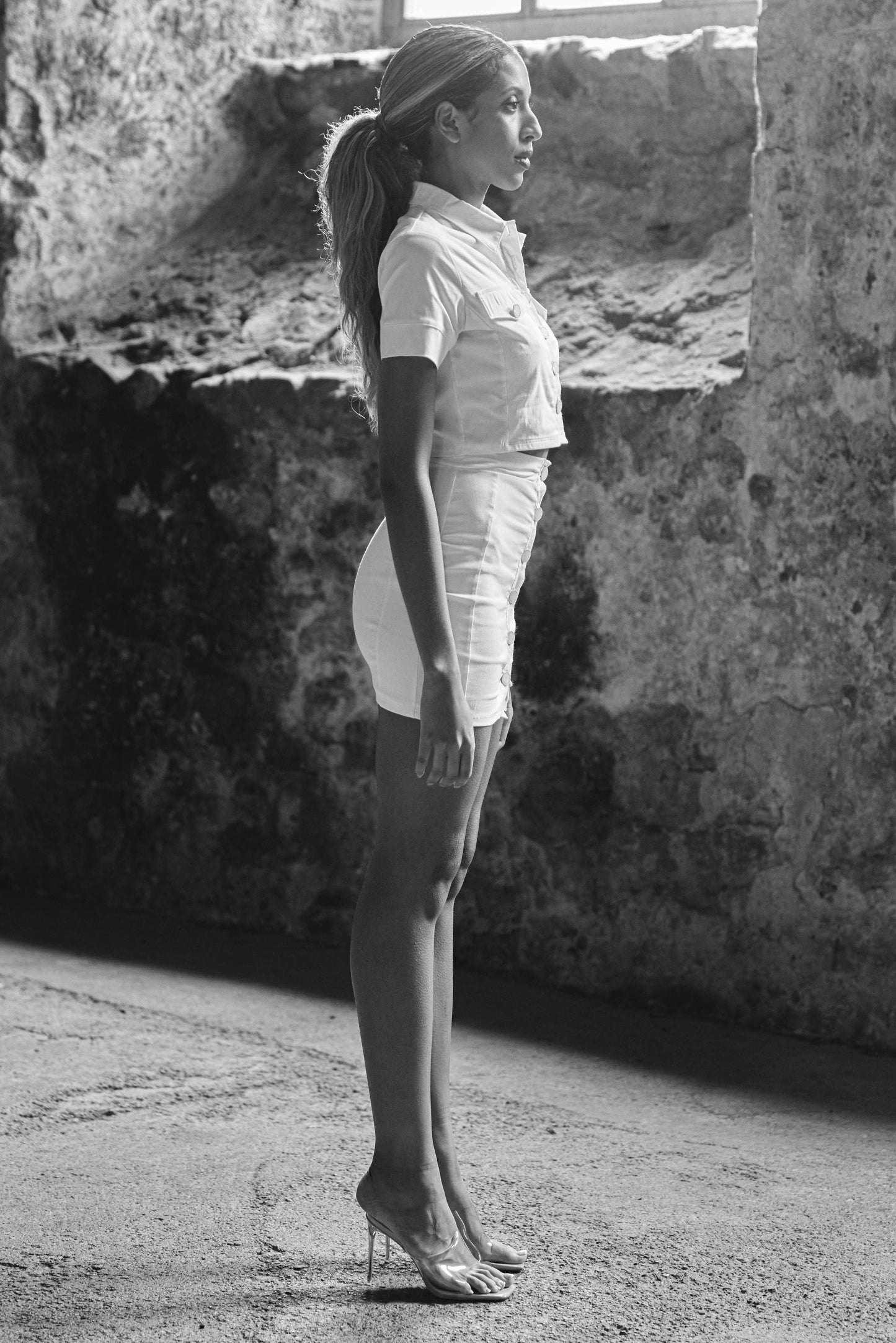 side view of model wearing matching button down skirt and crop top in cream