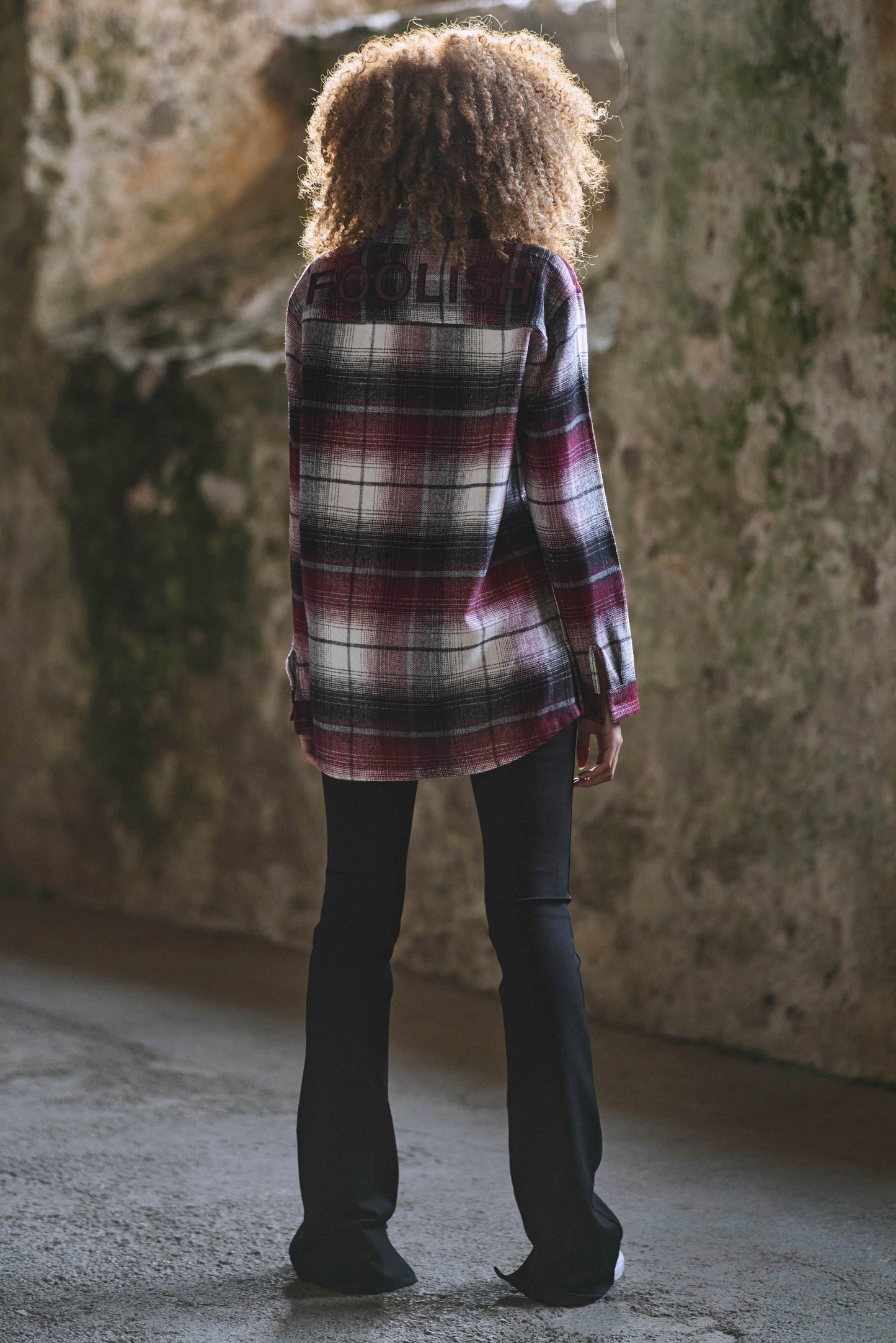 back view of model styled in luxury womens flared pants and check overshirt