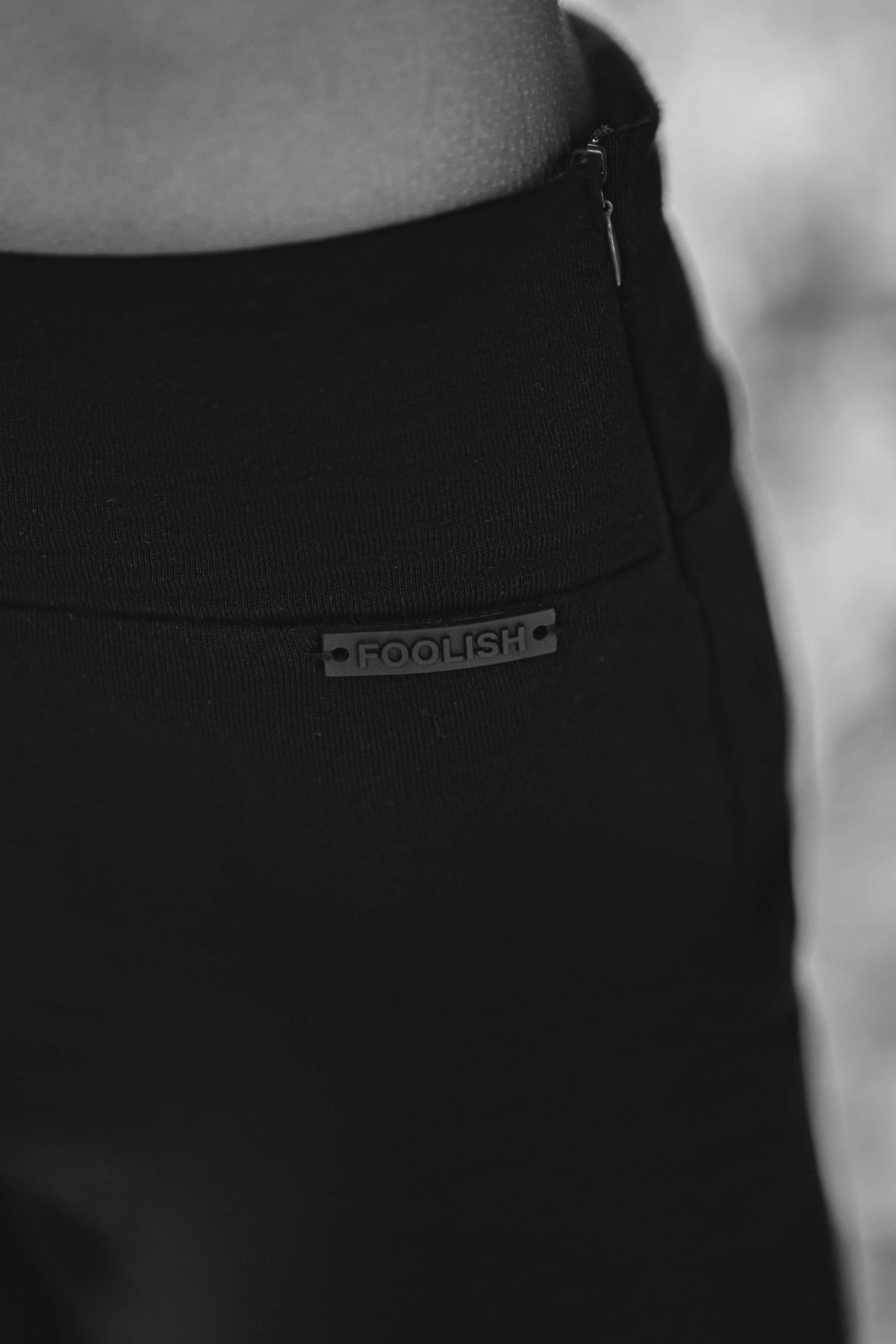 close up of branding detail on womens black split hem pants
