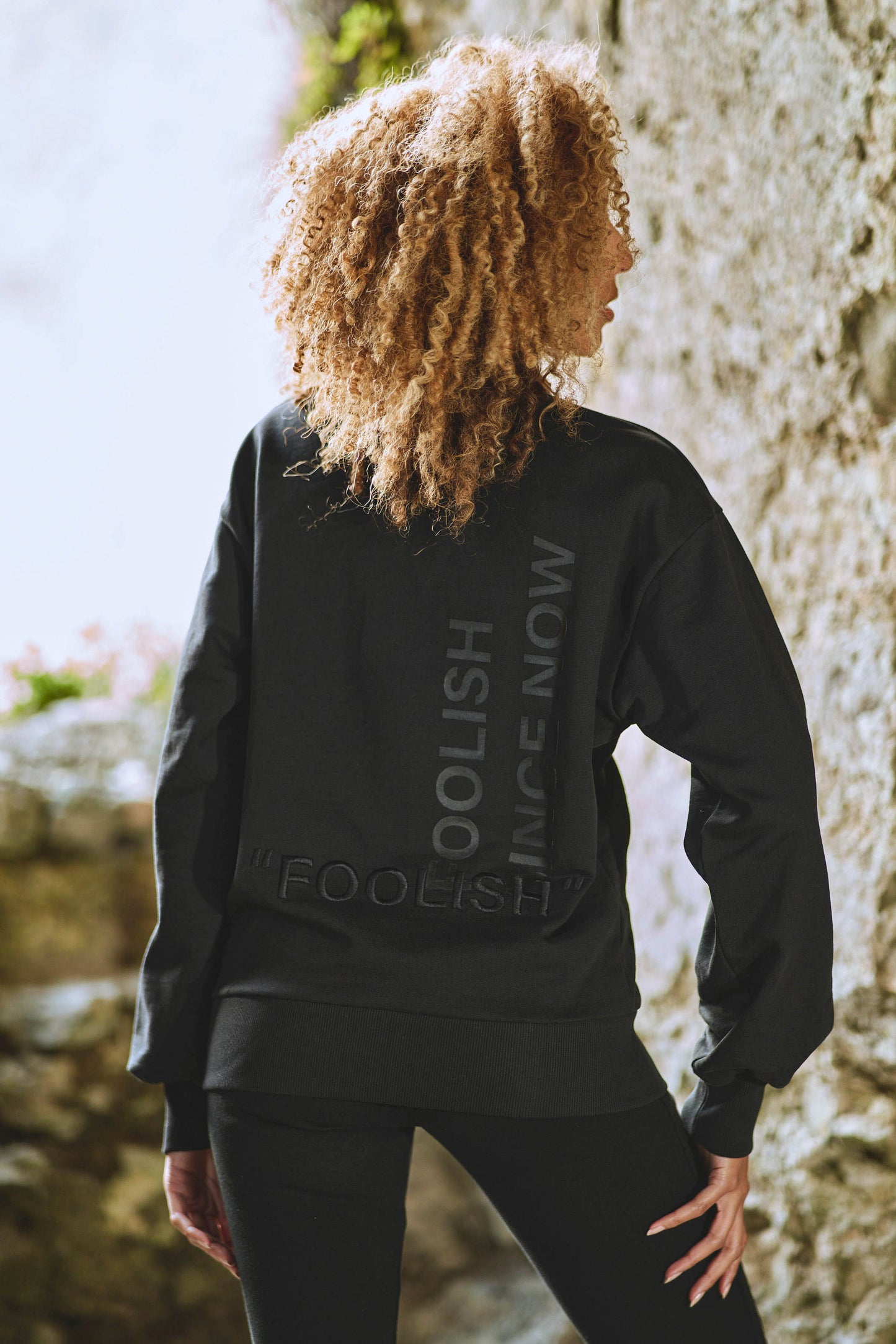 model posing to show back detail on luxury athleisure sweatshirt in black