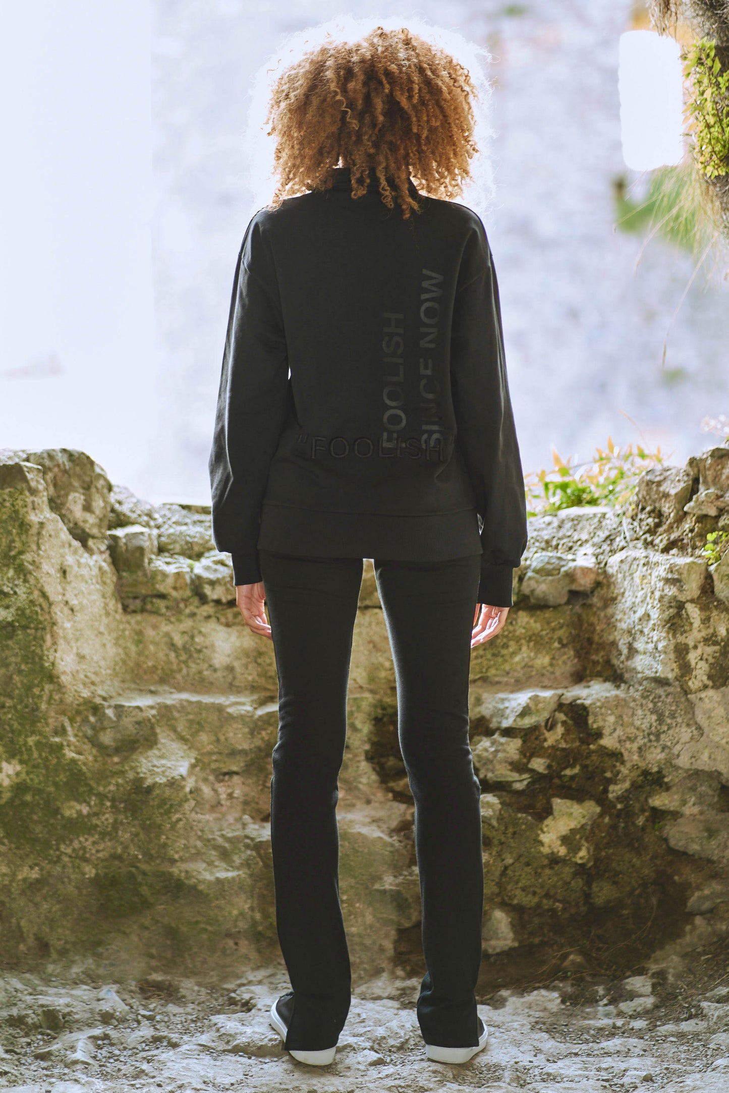 back view of model in branded sweatshirt and womens luxury pants with split hem