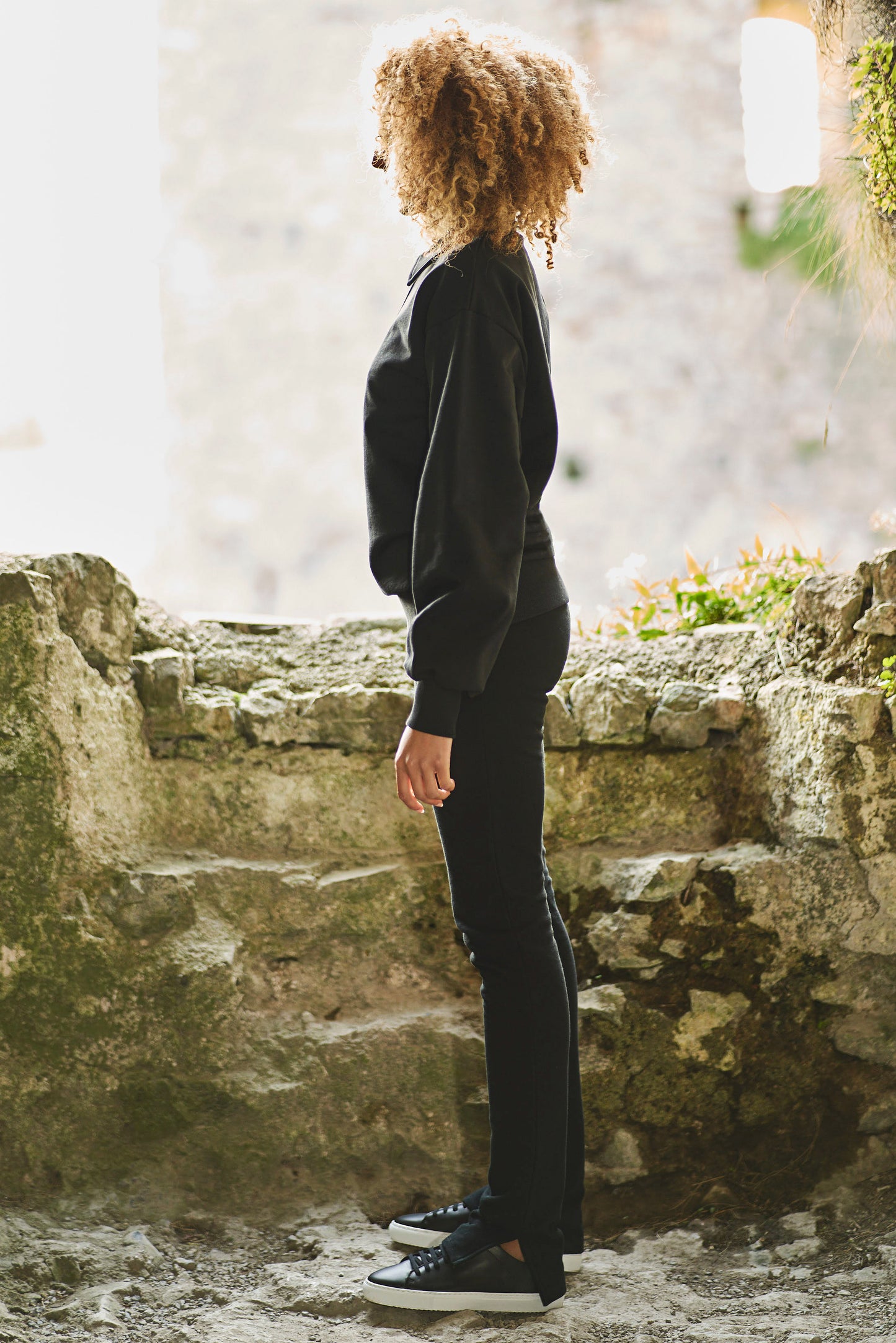 side view of model styled in split hem black pants and sweatshirt