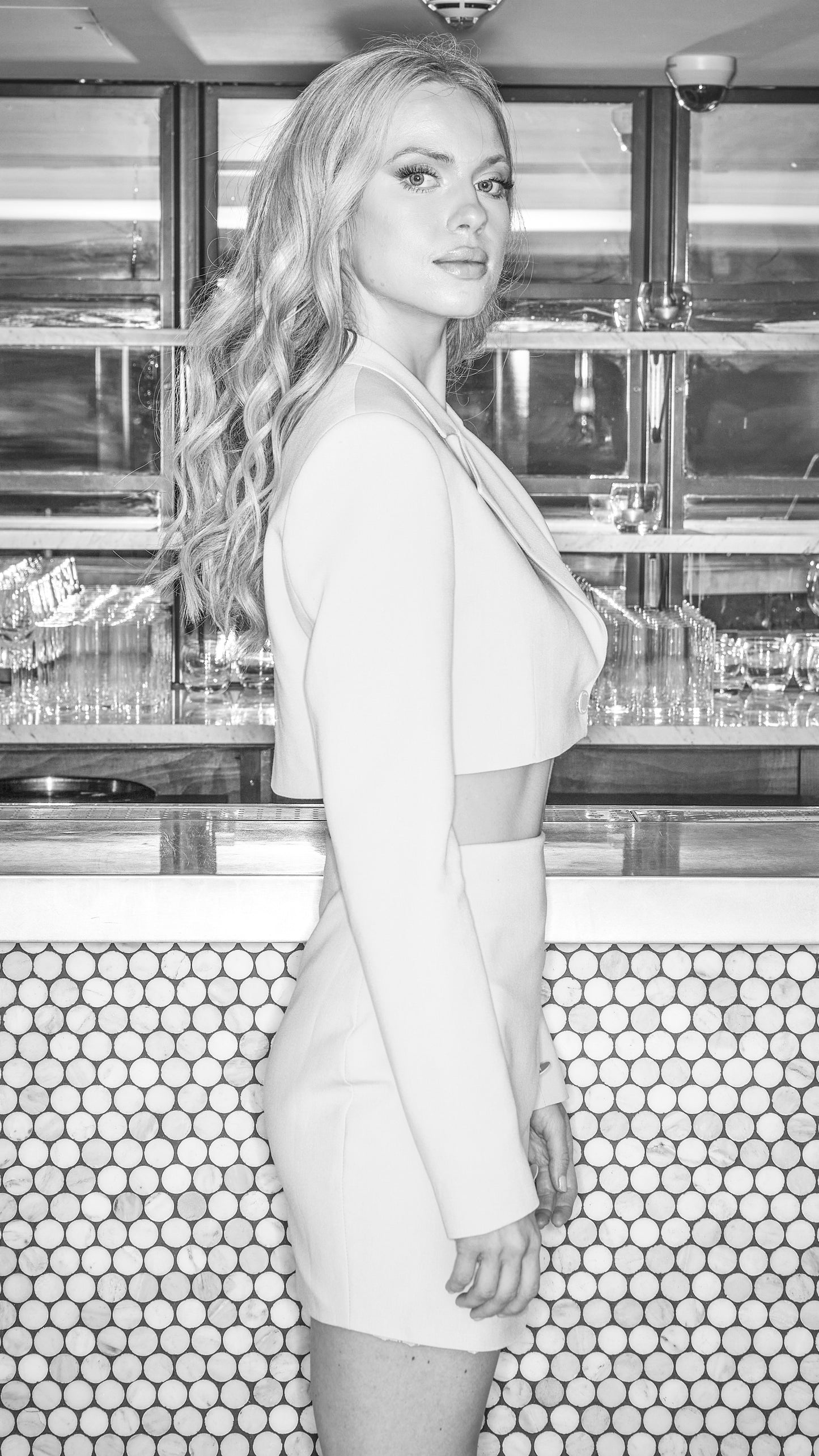 black and white image of model posing in stone coloured luxury skirt and blazer