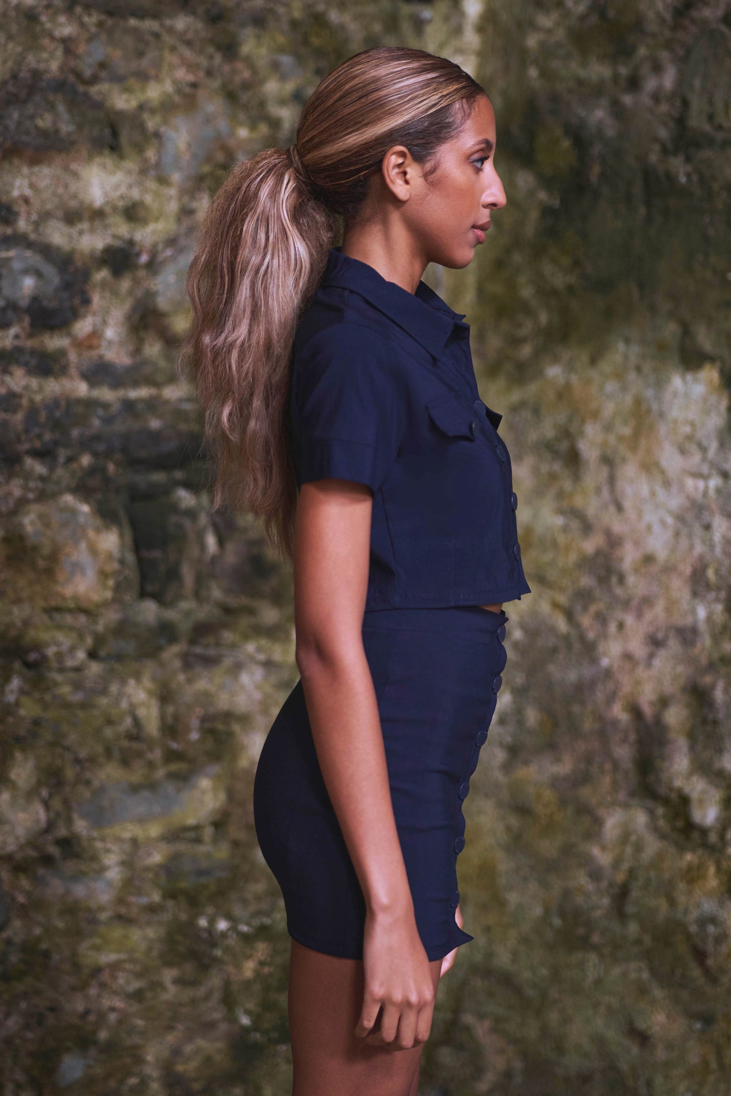 side view of model wearing matching navy crop top and luxury skirt