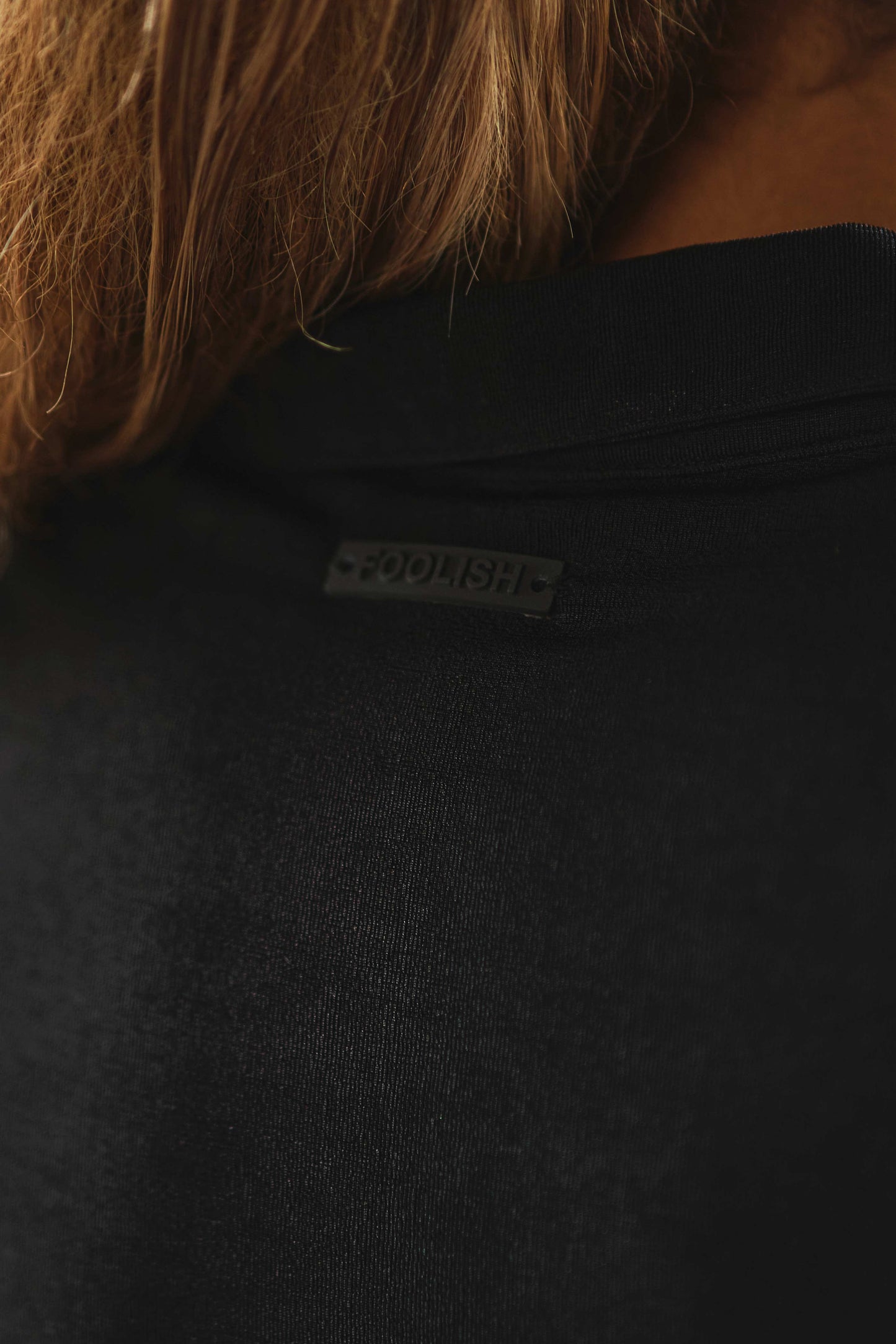 close up branded detailing on back of luxury womens dress in black