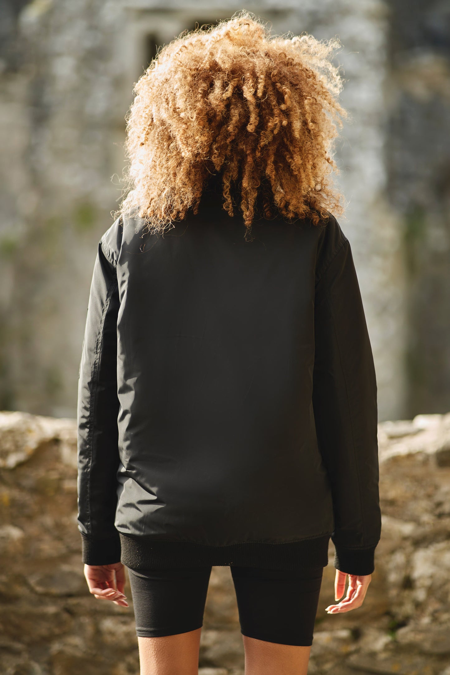 back view of womens contemporary bomber jacket in black