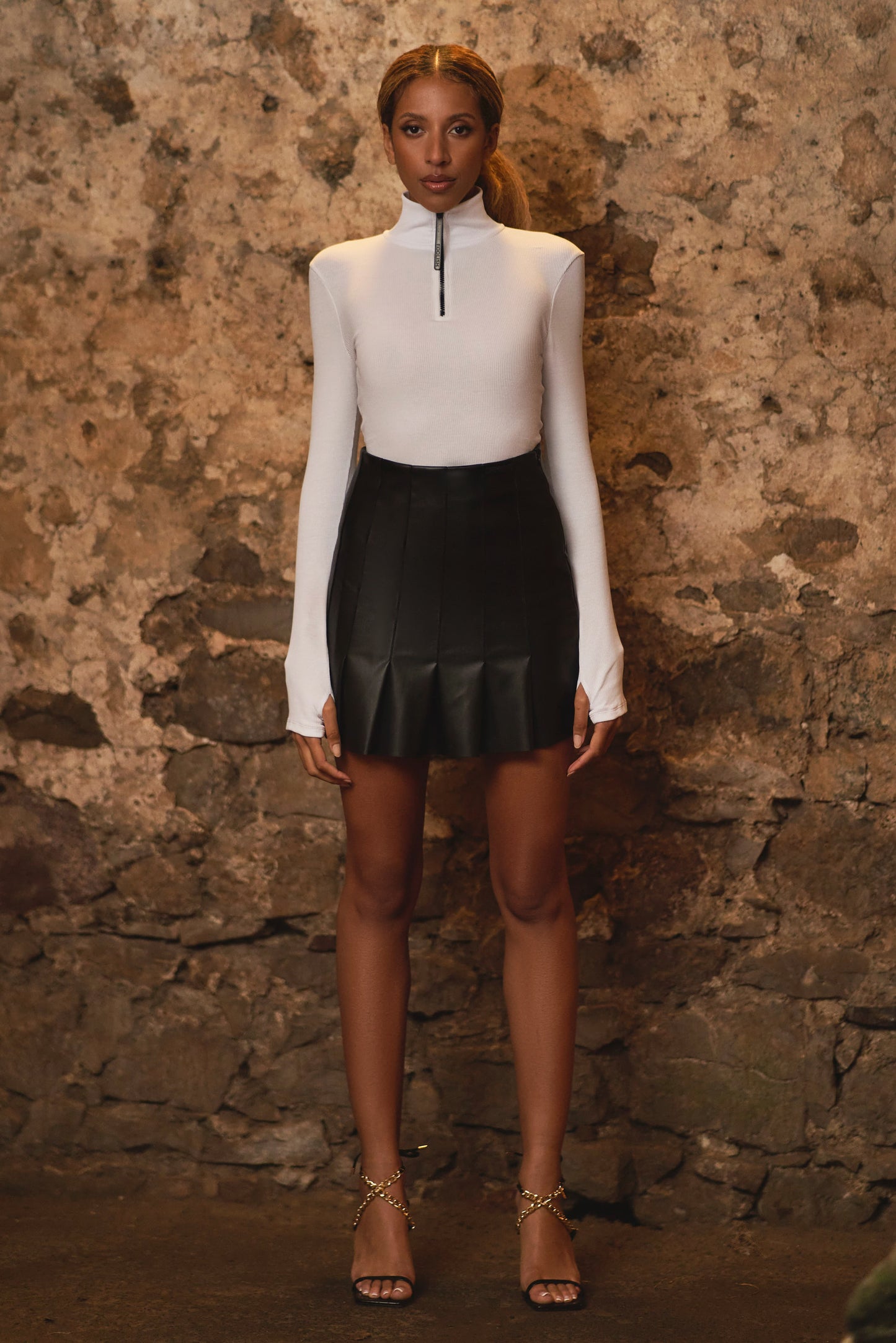 full length shot of model wearing pleated black leather skirt with bodysuit