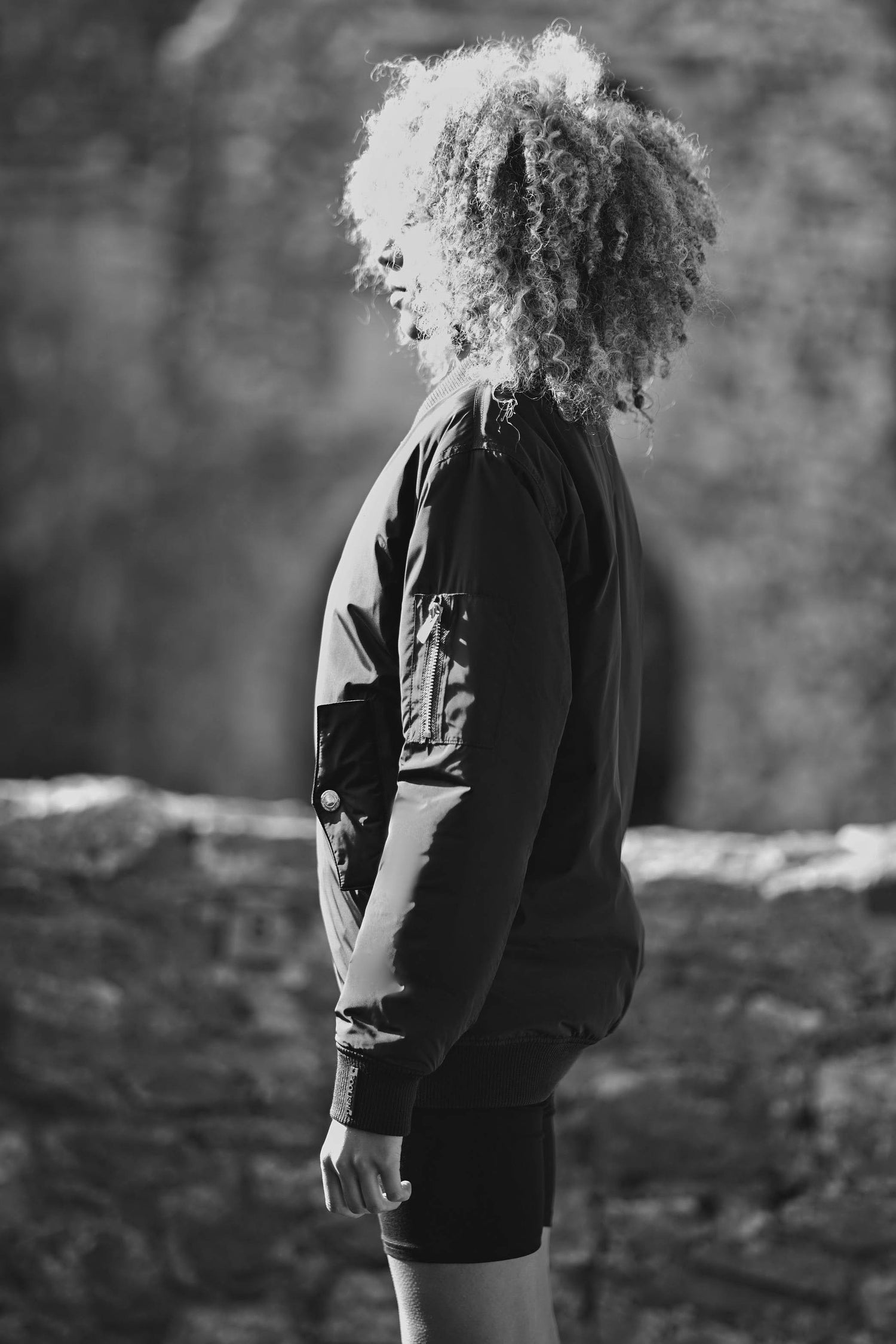 side view of model wearing contemporary bomber jacket in burgundy