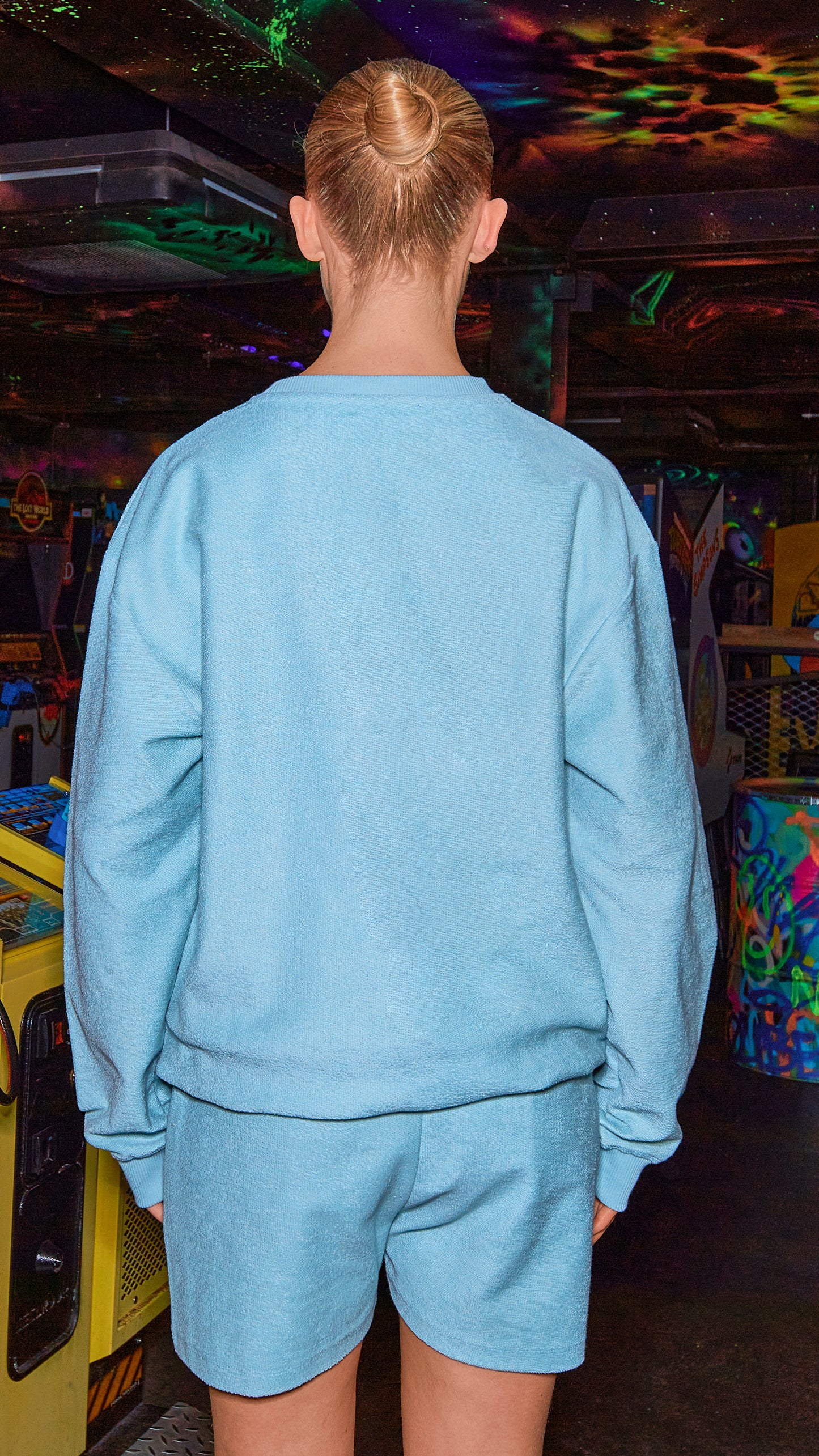 back view of model wearing chalk blue luxury sweatshirt and matching shorts